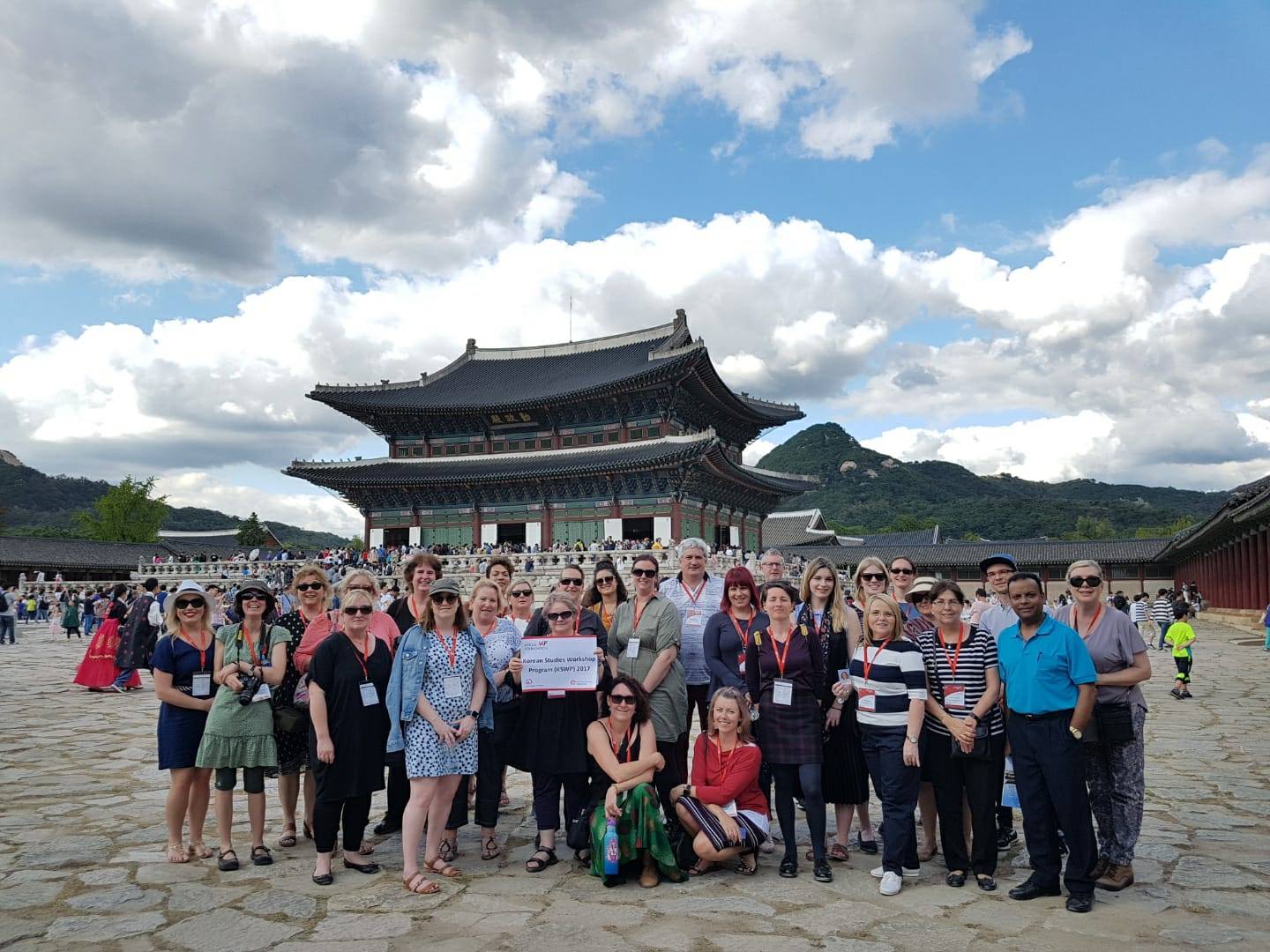 A diverse group of individuals smiling and posing together in front of a traditional pagoda structure.
