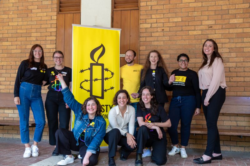 A group of diverse individuals stand in front of the event's banner