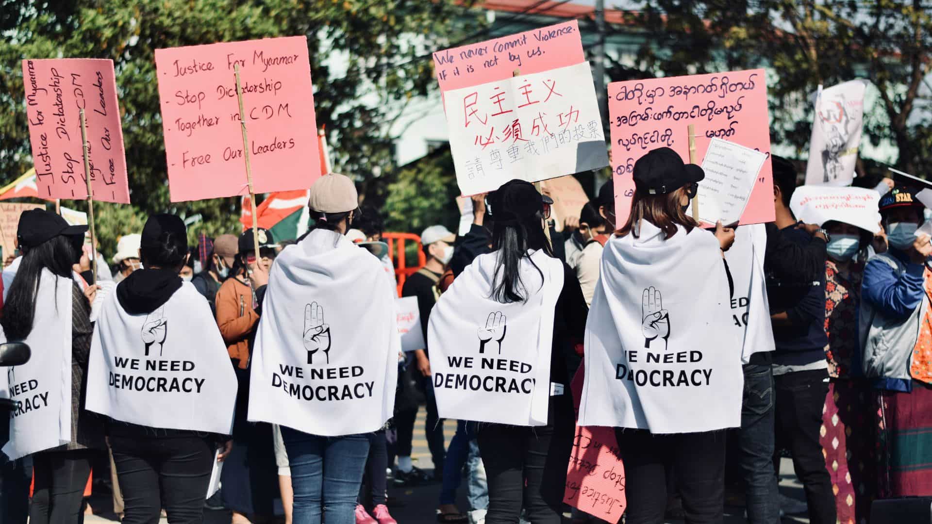 People holding signs in a protest advocating for democracy in Myanmar.