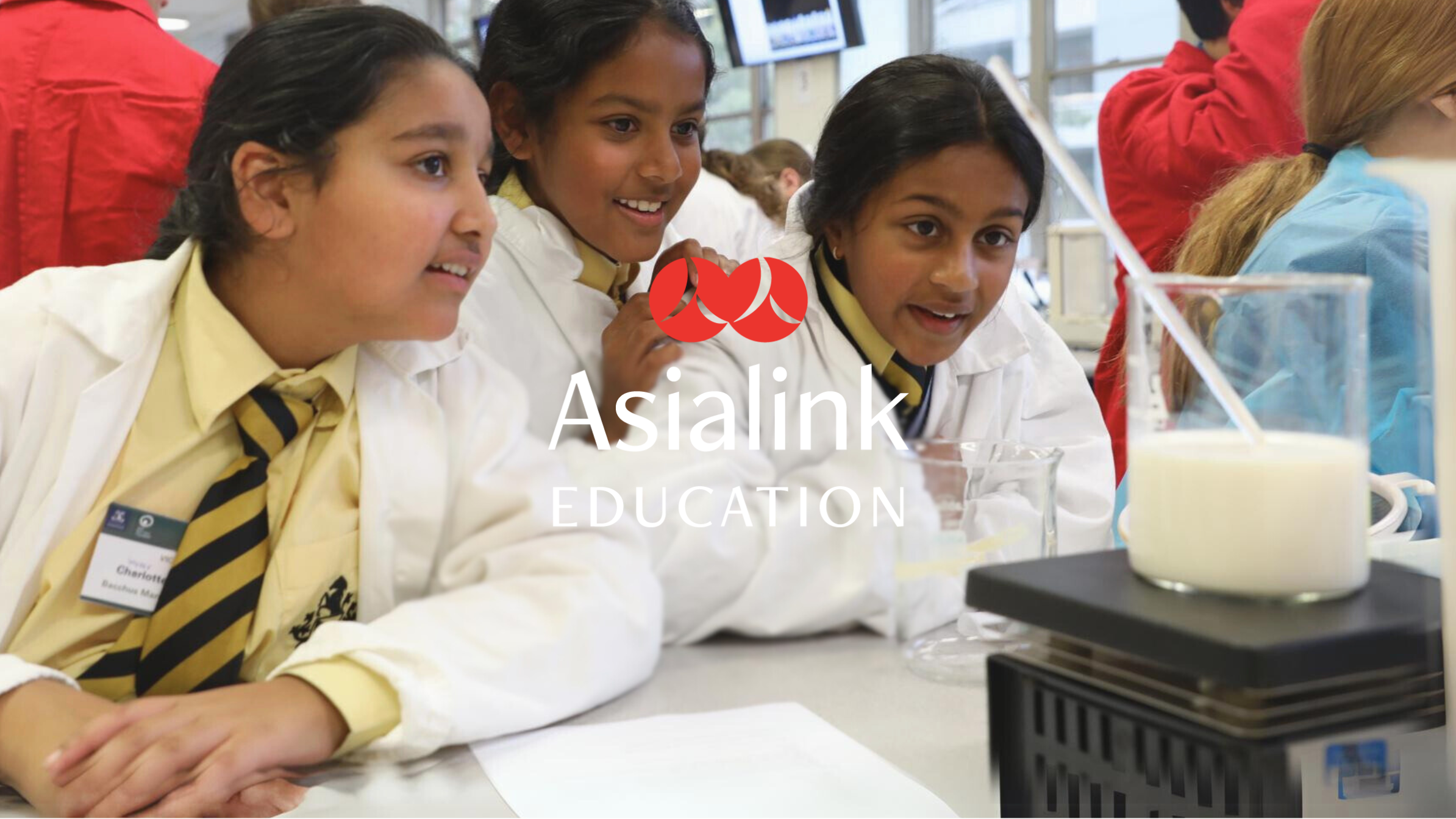 Three young students in lab coats eagerly observe a science experiment.