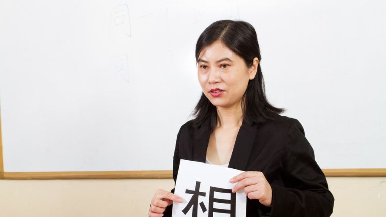 An asian woman holding a piece of paper written with Chinese character