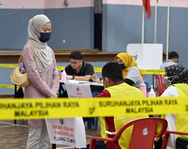A women wears a face mask while voting during the 15th General Election