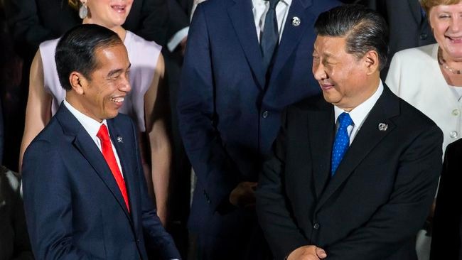 Widodo speaks with Xi during a family photo session at the G20 Summit in Osaka