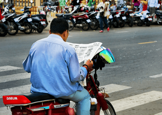 Man reading a newspaper on his motorbike in Phnom Penh, Cambodia